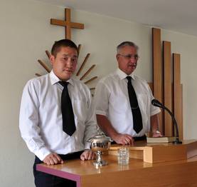 Bezirksapostel Nadolny mit Dolmetscher, Diakon Togo, am Altar in Ulan Bator
