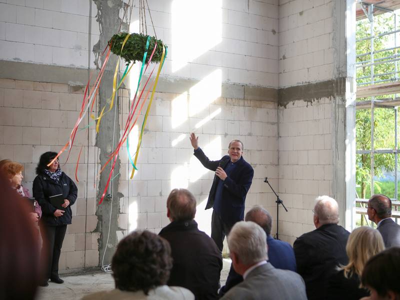 Pfarrer Gestrich weist auf das Kreuz in der Wand